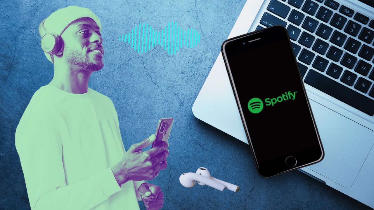 A man listening to music on his mobile phone, a laptop and an iPhone with Spotify app on the desk. Upload music to Spotify.