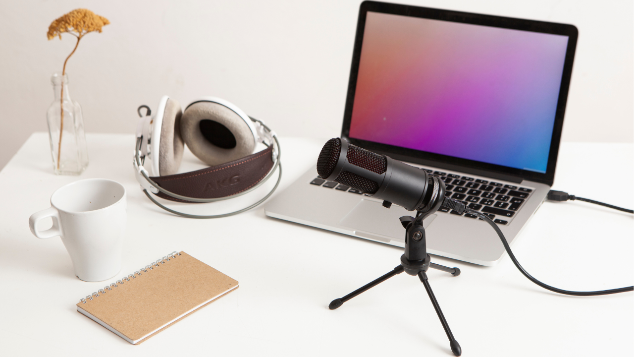 Laptop, microphone, and headphones are on the table for recording audio files.