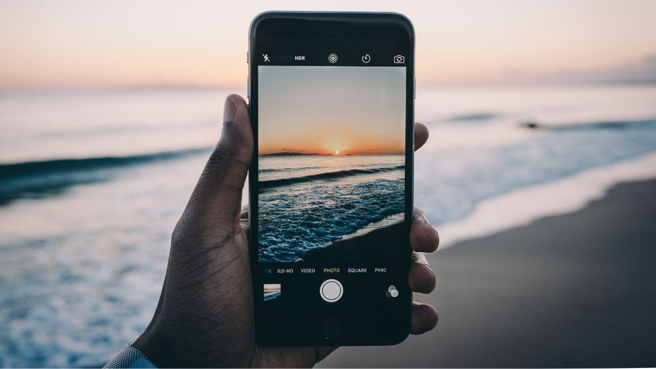 The Best Photo Settings for iPhone: a man taking a photo of the sunset